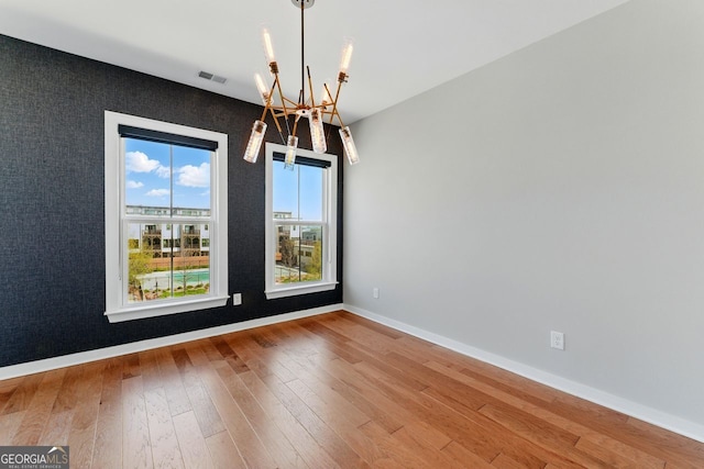 interior space with hardwood / wood-style floors, a notable chandelier, baseboards, and visible vents