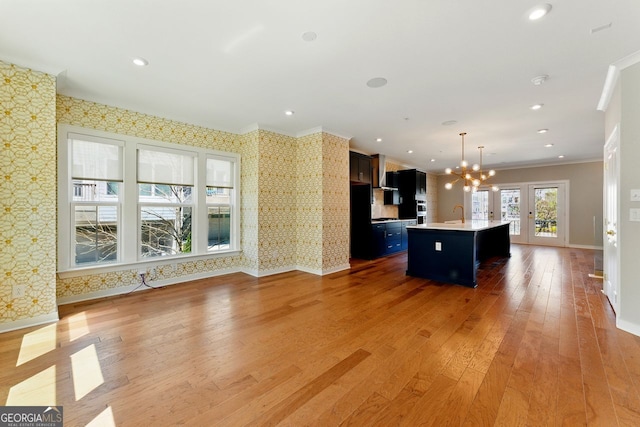 kitchen featuring light wood-style flooring, baseboards, a chandelier, wallpapered walls, and light countertops