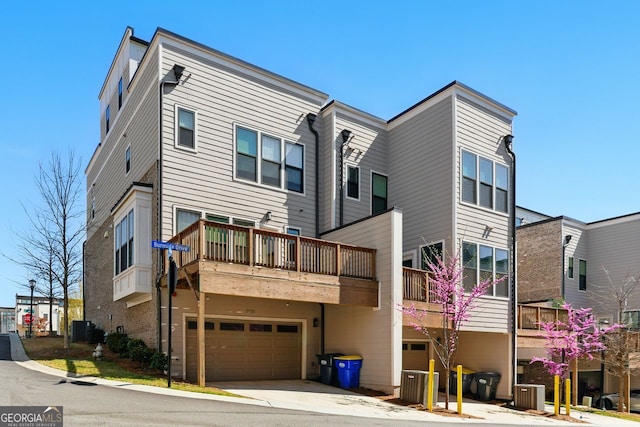 rear view of property featuring an attached garage, cooling unit, and driveway