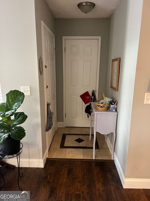 entrance foyer featuring a textured ceiling, baseboards, and wood finished floors