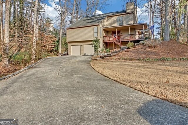 view of front of house featuring aphalt driveway, stairway, an attached garage, and a chimney
