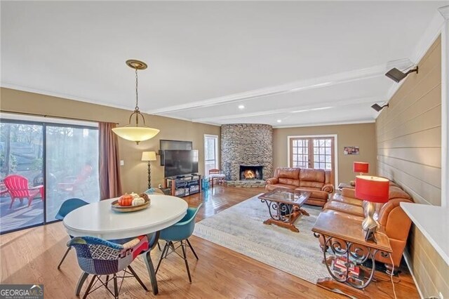 dining area featuring wood finished floors, crown molding, a fireplace, and beamed ceiling