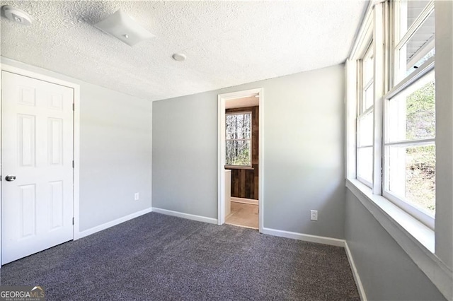 6886 Upshaw Mill Rd, Douglasville, GA 30134 - unfurnished bedroom featuring a textured ceiling, dark colored carpet, baseboards, multiple windows, and connected bathroom