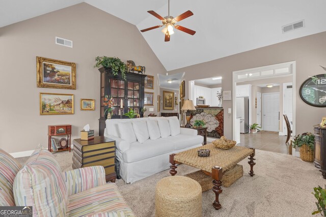 living room featuring high vaulted ceiling, ceiling fan, baseboards, and light colored carpet