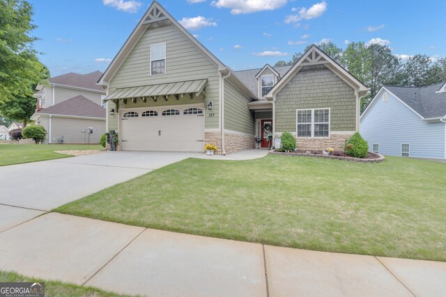view of front of home featuring stone siding, driveway, a front yard, and an attached garage