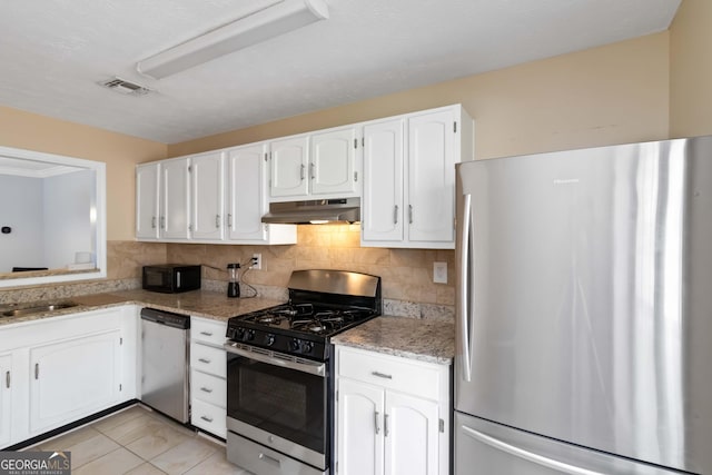 kitchen featuring under cabinet range hood, stainless steel appliances, visible vents, tasteful backsplash, and white cabinetry