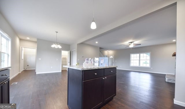 kitchen featuring ceiling fan with notable chandelier, open floor plan, baseboards, decorative light fixtures, and dark wood-type flooring