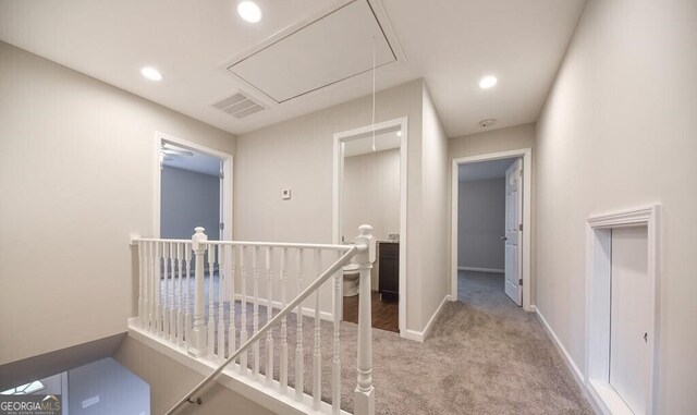 hallway featuring an upstairs landing, attic access, carpet, baseboards, and visible vents