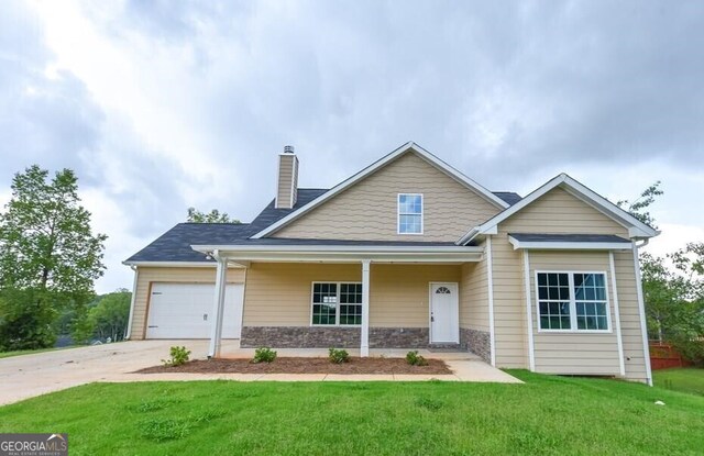 view of front of property featuring a front lawn, driveway, stone siding, and a chimney