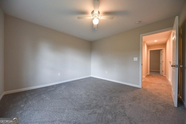 carpeted spare room featuring baseboards and ceiling fan