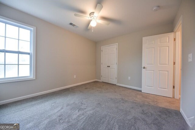 unfurnished bedroom featuring baseboards, visible vents, carpet, and a ceiling fan