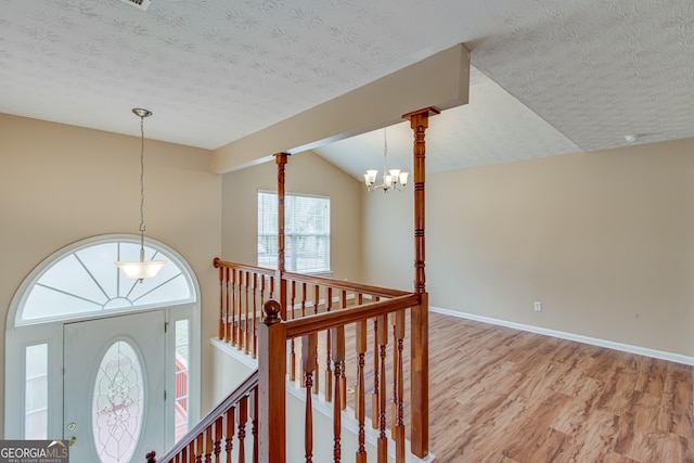 3024 Big Tree Rd, Gainesville, GA 30501 - staircase with a chandelier, wood finished floors, vaulted ceiling, baseboards, and a textured ceiling