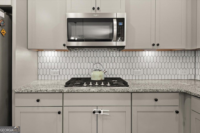 372 Garnet Dr, Acworth, GA 30101 - kitchen featuring appliances with stainless steel finishes, decorative backsplash, and light stone counters