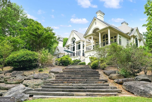 exterior space featuring a chimney, stucco siding, and stairway