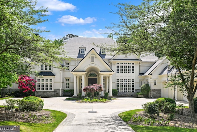 view of front of home with curved driveway, stucco siding, and stone siding