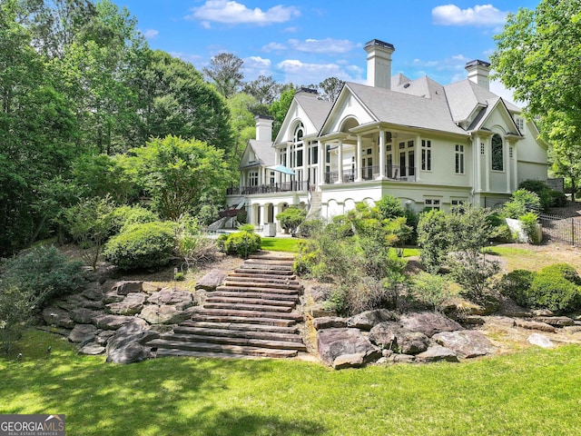 back of property with a lawn and a chimney