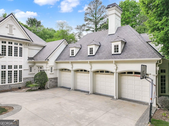view of front facade with stucco siding, a chimney, a shingled roof, an attached garage, and driveway