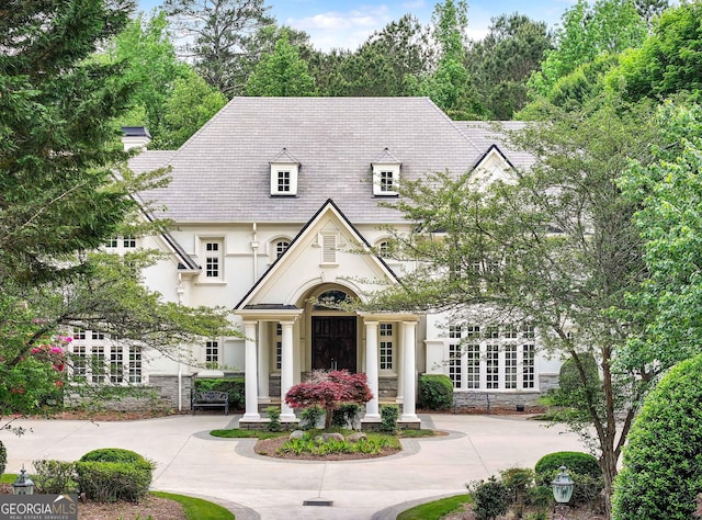 view of front of home featuring curved driveway, stucco siding, and stone siding