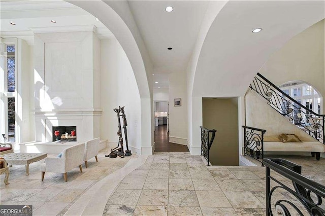 foyer with stone tile flooring, baseboards, recessed lighting, arched walkways, and a multi sided fireplace