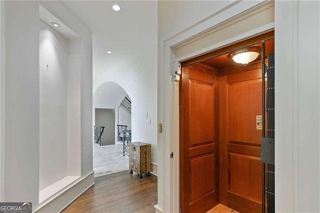 hall featuring arched walkways, a sauna, recessed lighting, and wood finished floors