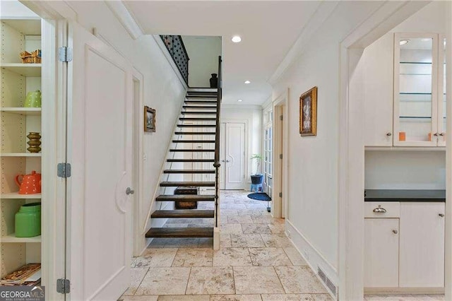interior space featuring visible vents, crown molding, baseboards, recessed lighting, and stone tile floors