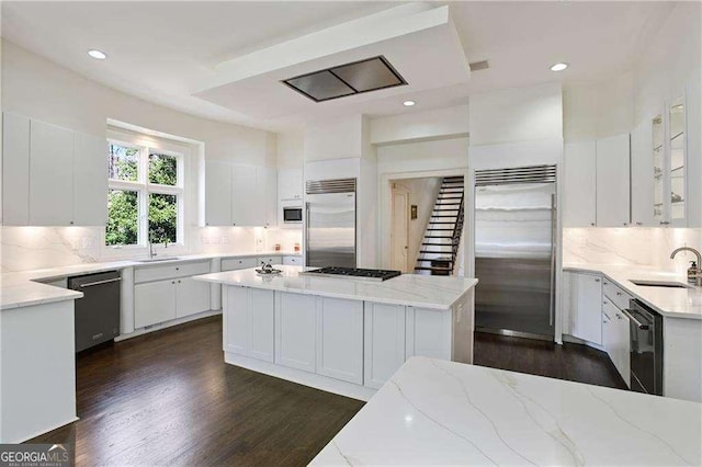 510 Covington Cv, Alpharetta, GA 30022 - kitchen featuring built in appliances, a sink, white cabinetry, decorative backsplash, and dark wood finished floors