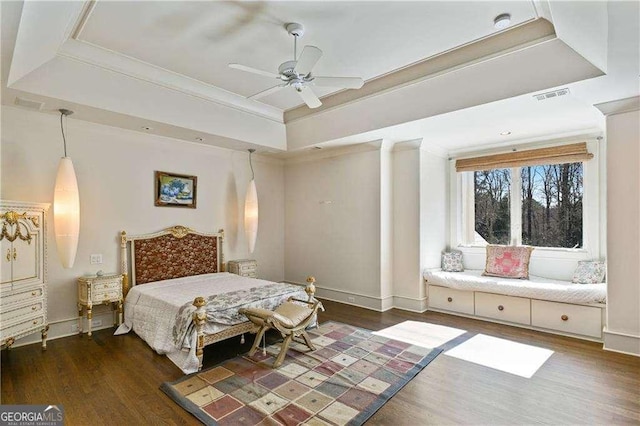 bedroom featuring baseboards, a raised ceiling, wood finished floors, and visible vents