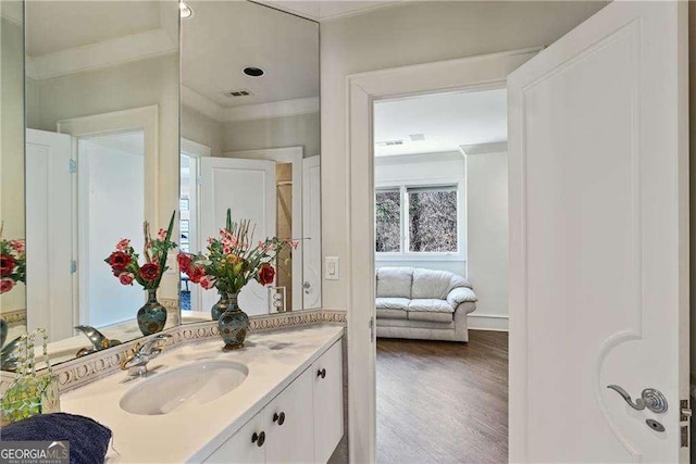 bathroom with a healthy amount of sunlight, vanity, crown molding, and wood finished floors