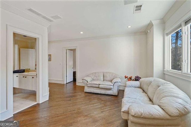 living room with visible vents, ornamental molding, baseboards, and wood finished floors