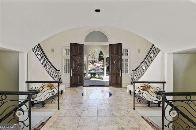 entrance foyer with stairs, arched walkways, and lofted ceiling