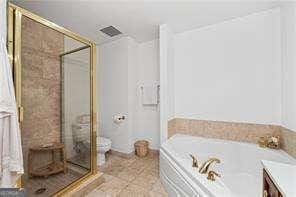 bathroom with a garden tub, a stall shower, toilet, and tile patterned flooring