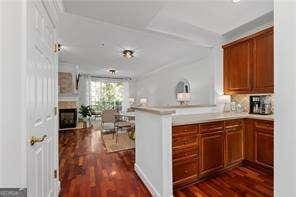 kitchen with dark wood finished floors, light countertops, brown cabinets, a peninsula, and a fireplace