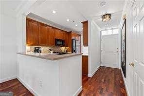 kitchen featuring ornamental molding, dark wood finished floors, a peninsula, brown cabinetry, and light countertops