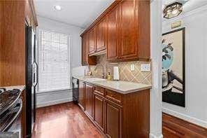 kitchen with backsplash, dark wood-style floors, brown cabinetry, light countertops, and stainless steel range with gas stovetop