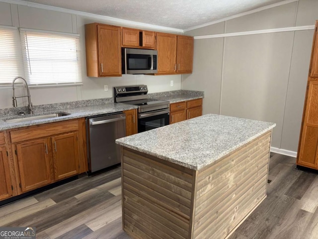 kitchen featuring brown cabinets, ornamental molding, a sink, appliances with stainless steel finishes, and dark wood-style flooring