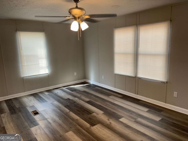 spare room with baseboards, visible vents, dark wood-style flooring, and ceiling fan