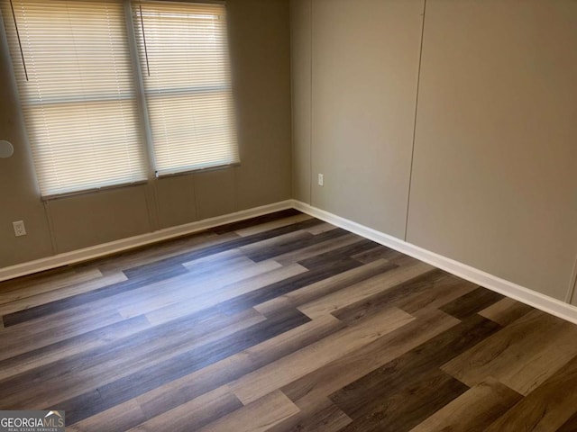 empty room featuring baseboards and dark wood-style flooring