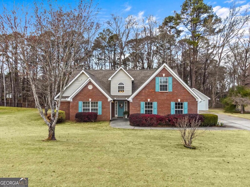 traditional-style home with a front lawn, concrete driveway, brick siding, and a shingled roof