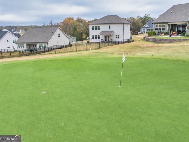 view of property's community with view of golf course, a lawn, fence, and a residential view