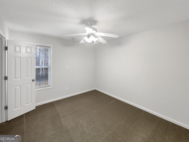 unfurnished room featuring a textured ceiling, baseboards, a ceiling fan, and dark colored carpet