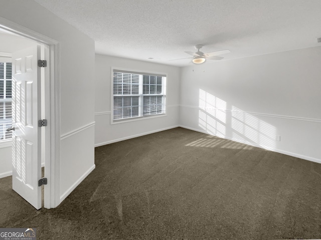 unfurnished room featuring baseboards, dark carpet, a textured ceiling, and a ceiling fan
