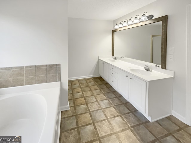 full bathroom with double vanity, a garden tub, baseboards, and a sink