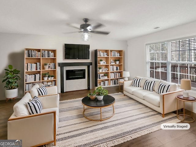 living room featuring a glass covered fireplace and a ceiling fan