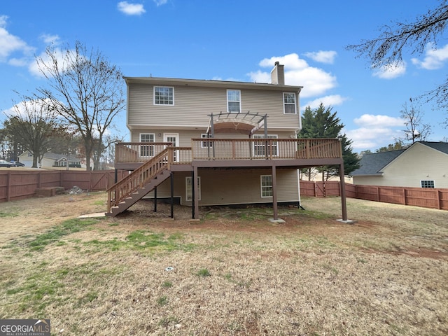 back of house with stairway, a wooden deck, a yard, a fenced backyard, and a chimney