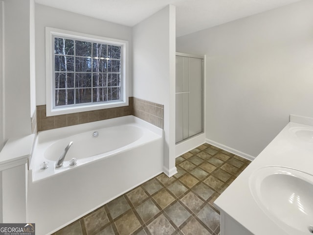 full bathroom with a garden tub, double vanity, a shower stall, and a sink