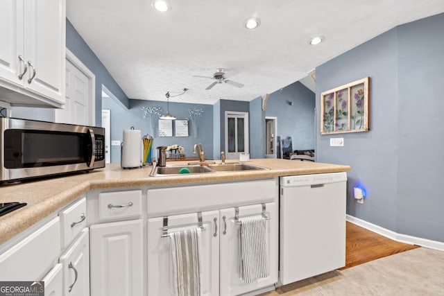kitchen featuring stainless steel microwave, a peninsula, a sink, dishwasher, and a ceiling fan