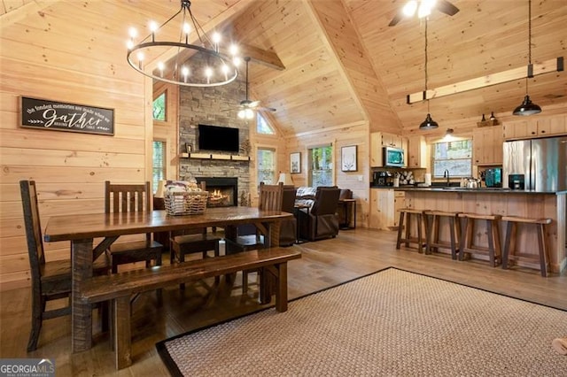 dining room featuring wood ceiling, light wood-style floors, and ceiling fan with notable chandelier