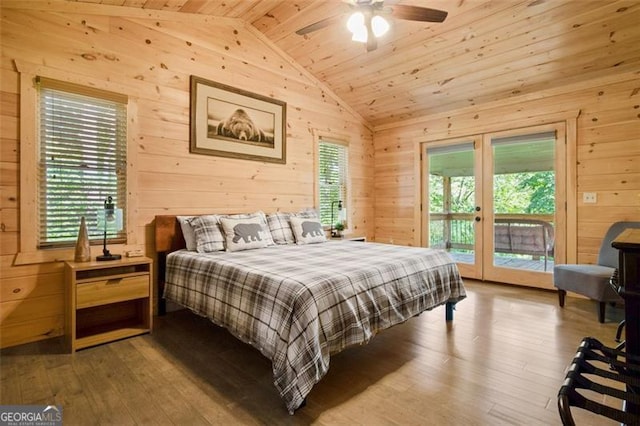 bedroom featuring wooden walls, multiple windows, wood finished floors, and vaulted ceiling