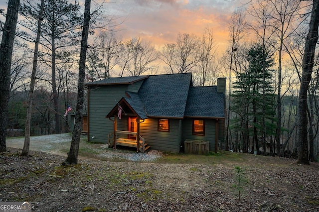 chalet / cabin featuring roof with shingles and a chimney
