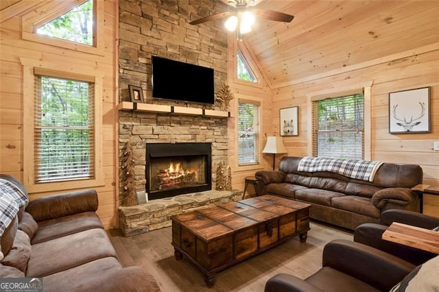 living area featuring plenty of natural light, wooden walls, wood finished floors, and ceiling fan